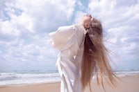 a woman with long hair standing on the beach