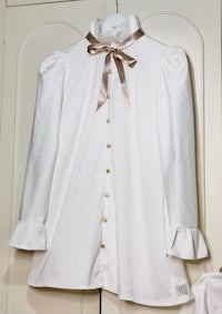 a white blouse with ruffles hanging on a door