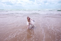 a girl sitting on a chair in the ocean