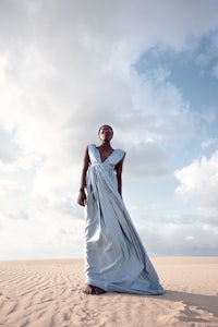 a woman in a blue dress standing in the desert