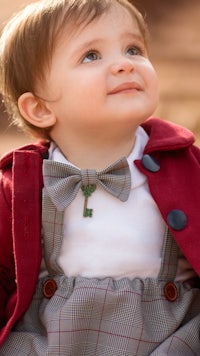 a little boy in a red coat and bow tie