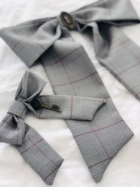 a grey and red plaid bow tie on a white bed