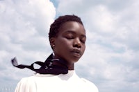 a black woman in a white shirt with a black scarf